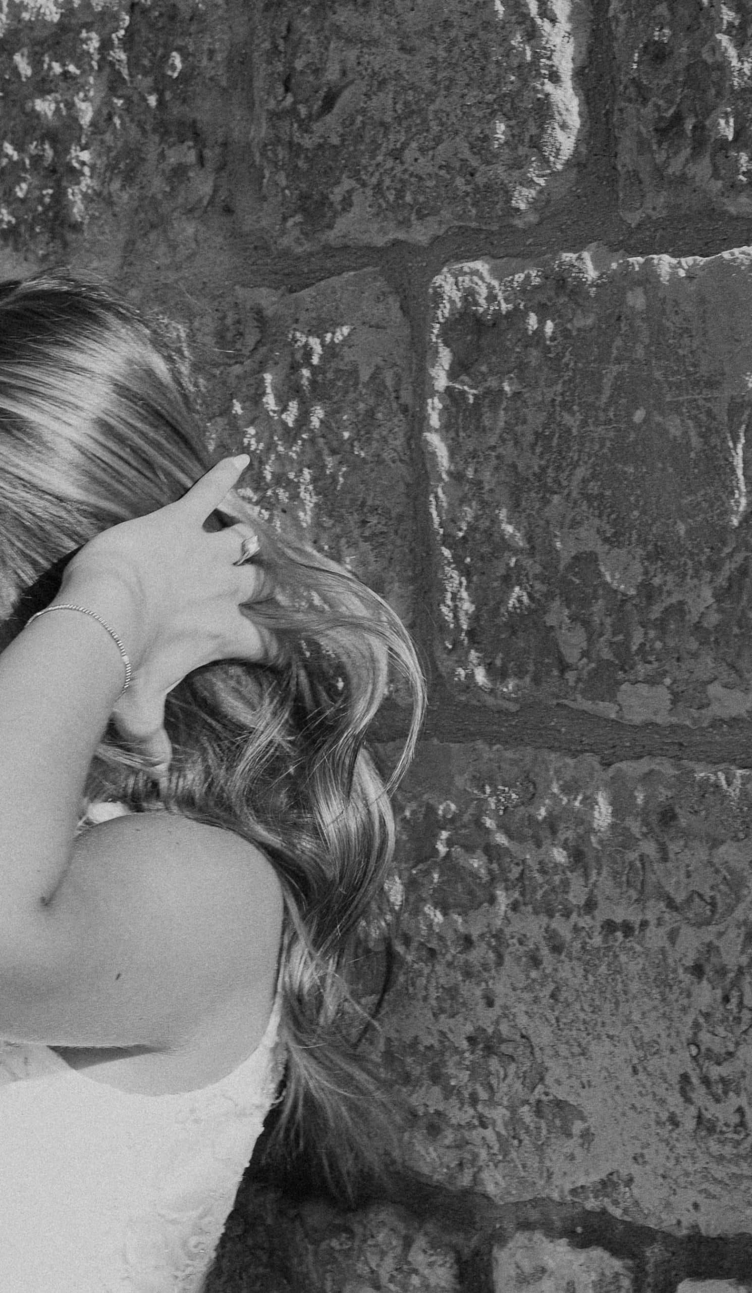 Crno-bijeli detalj: ruka mladenke s prstenom u kosi, pozadina starog kamenog zida, zaručničko fotografiranje Dalmacija.