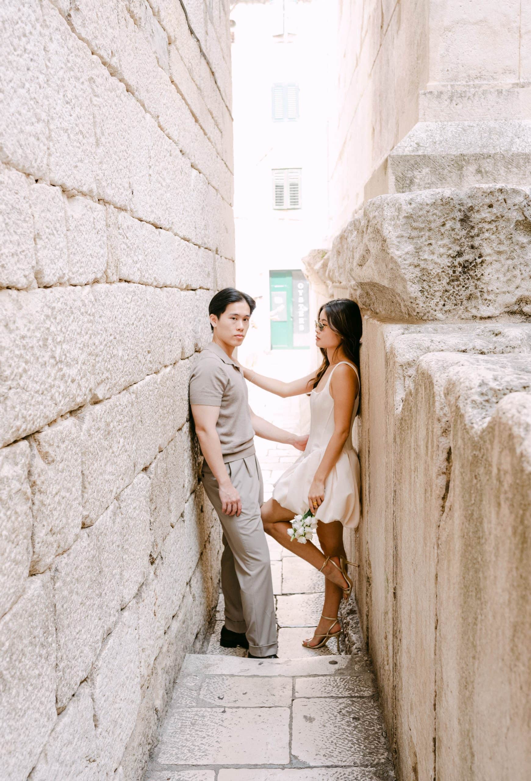 Vjenčani par u uskoj kamenoj uličici, držeći ruke jedan na drugome.