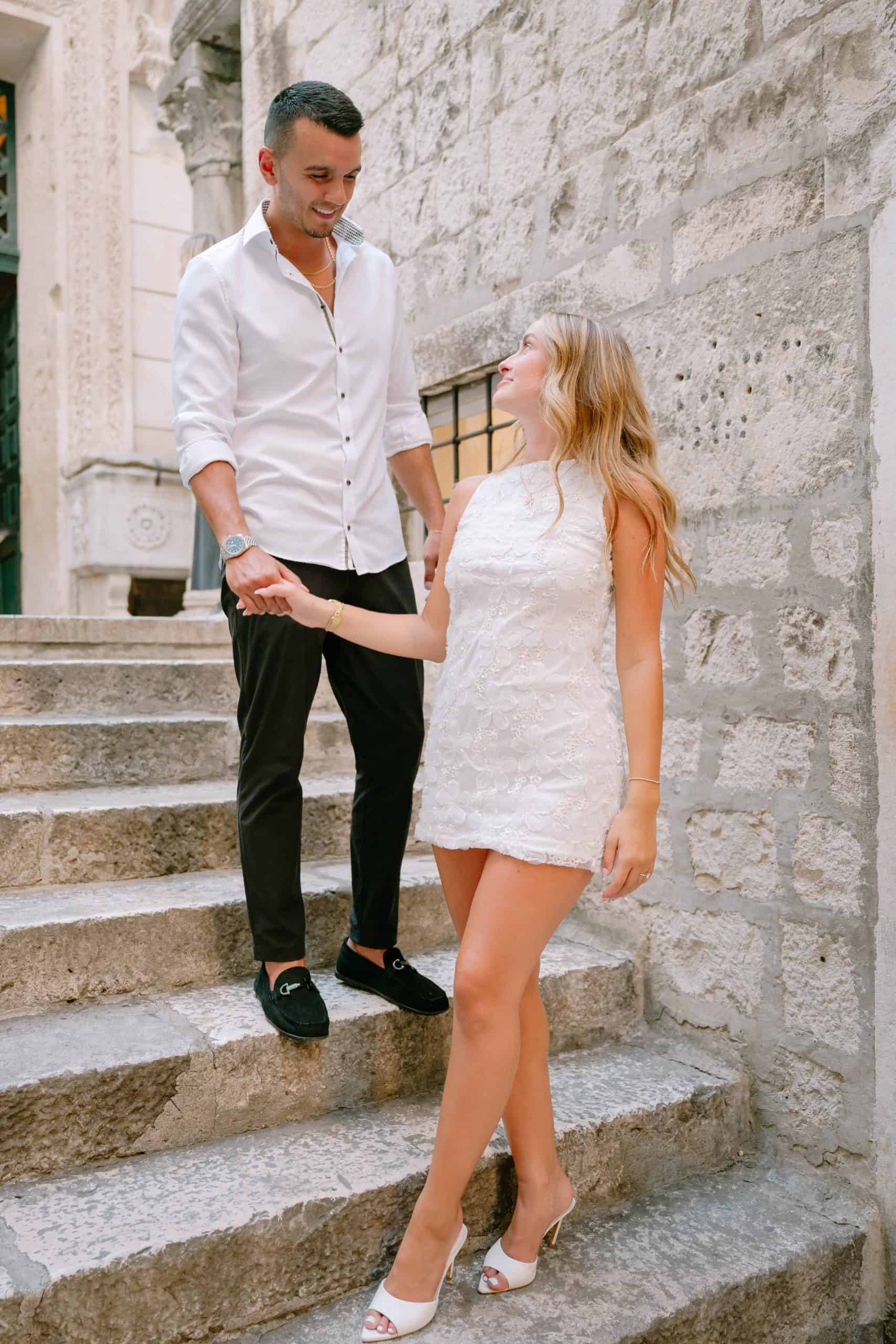 Par se drži za ruke na kamenim stepenicama u povijesnom okruženju grada Splita.