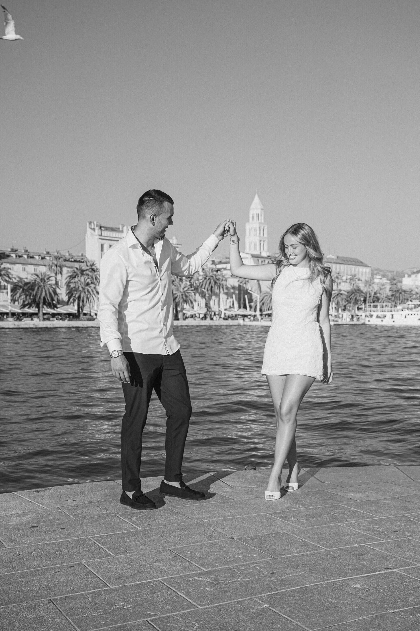 Zaljubljeni par pleše uz rivu u Splitu, Hrvatska, s povijesnom arhitekturom u pozadini.