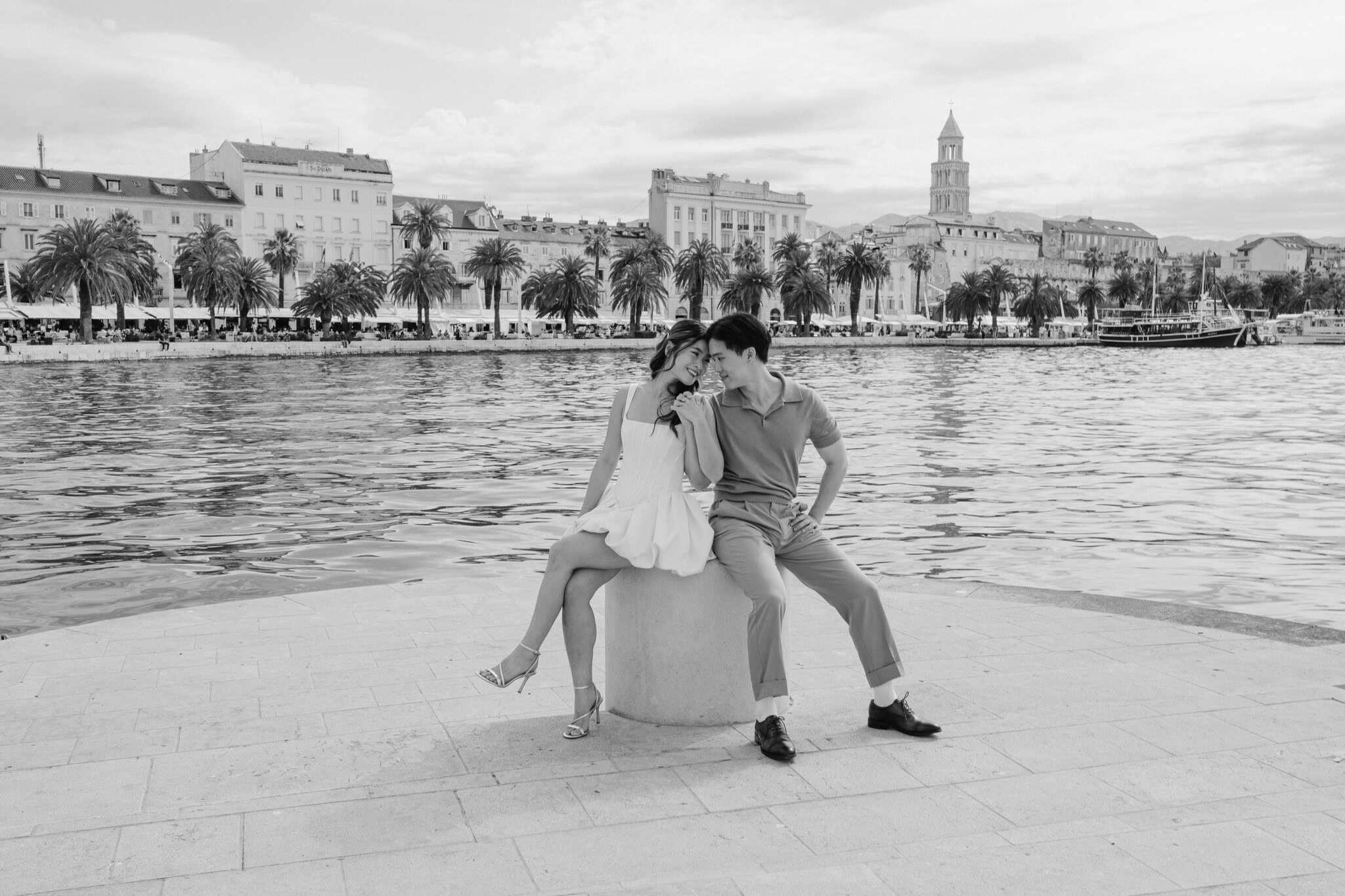 Uživanje u romantičnom trenutku uz more s gradskom panoramom u pozadini.