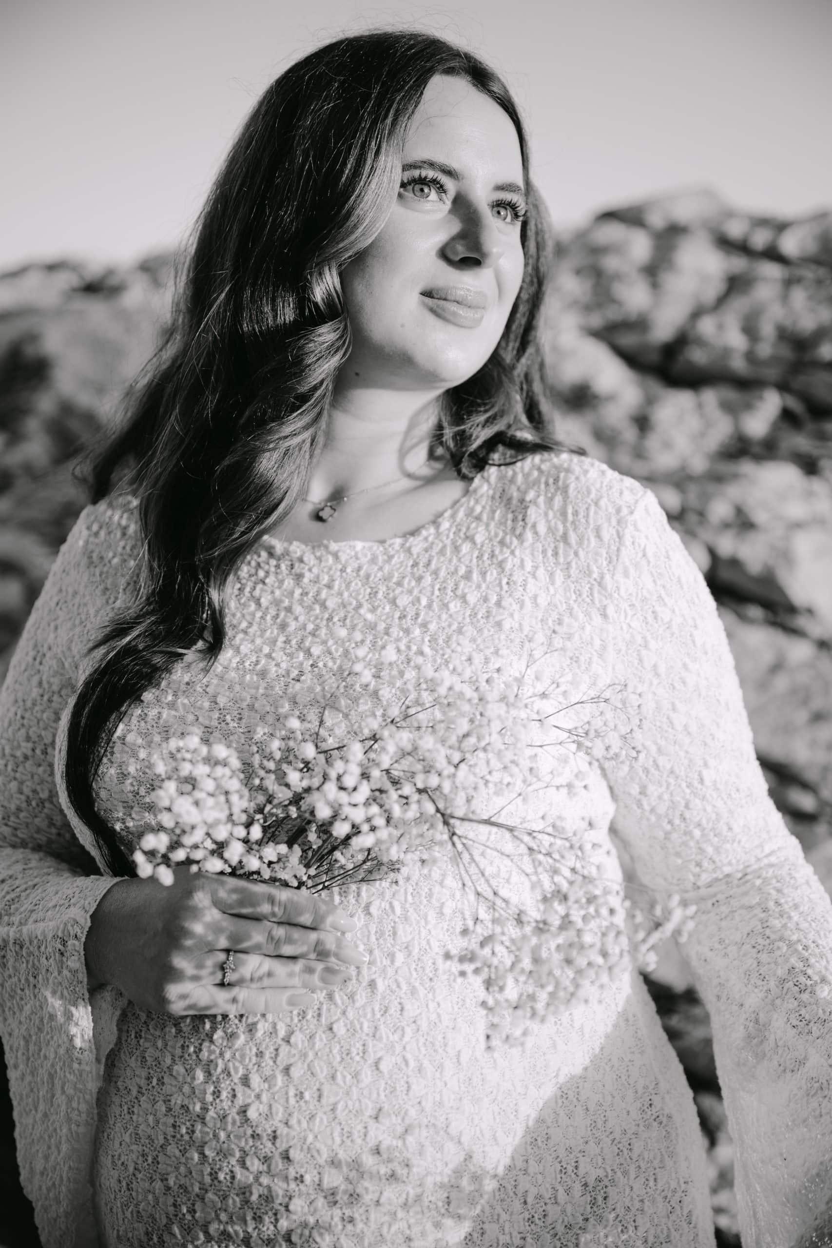 Žena s cvijećem u ruci na prirodnoj pozadini, portret u crno-bijeloj boji.