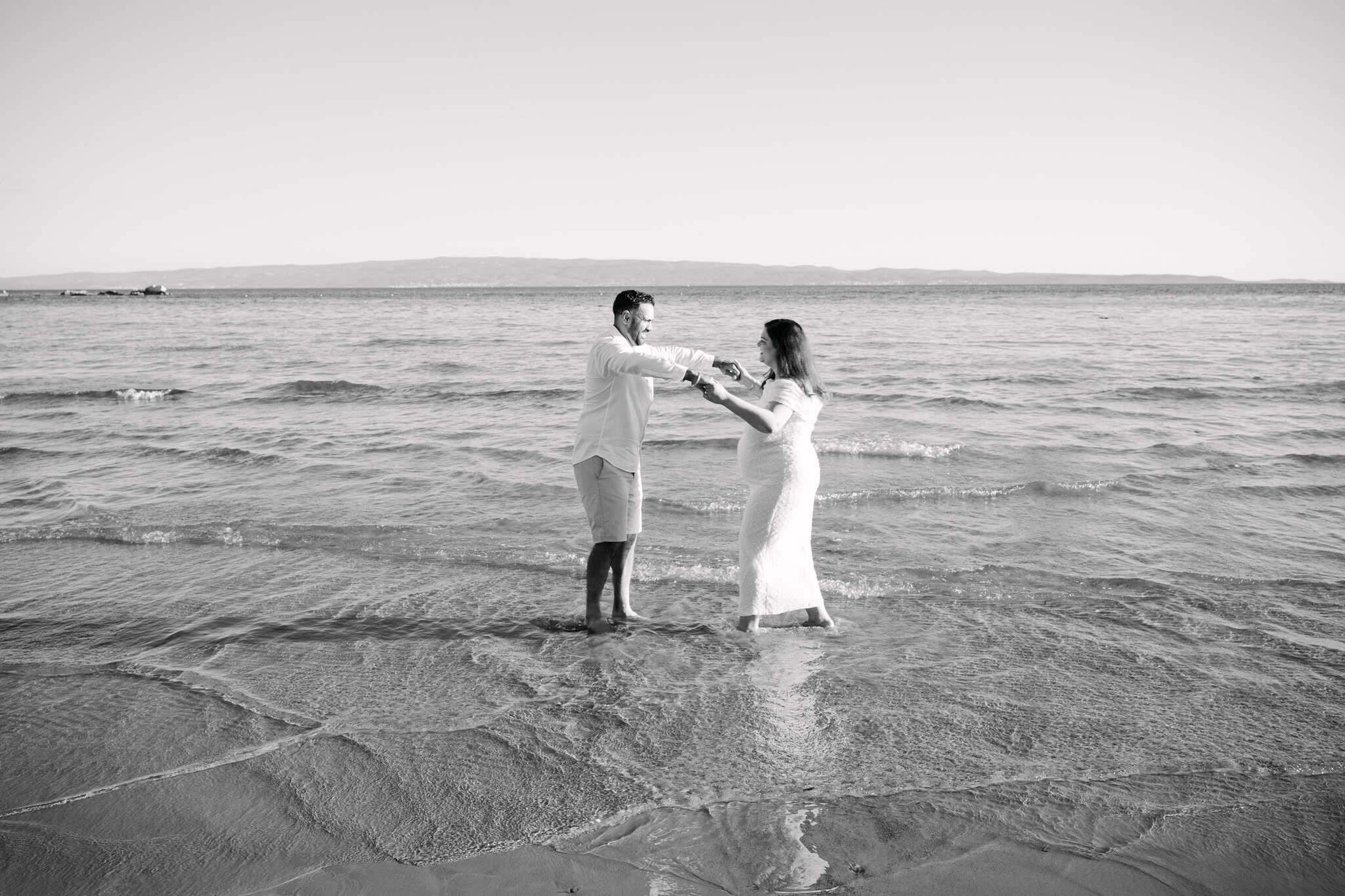 Budući roditelji plešu u plićaku na ljetnom maternity sessionu u Splitu.