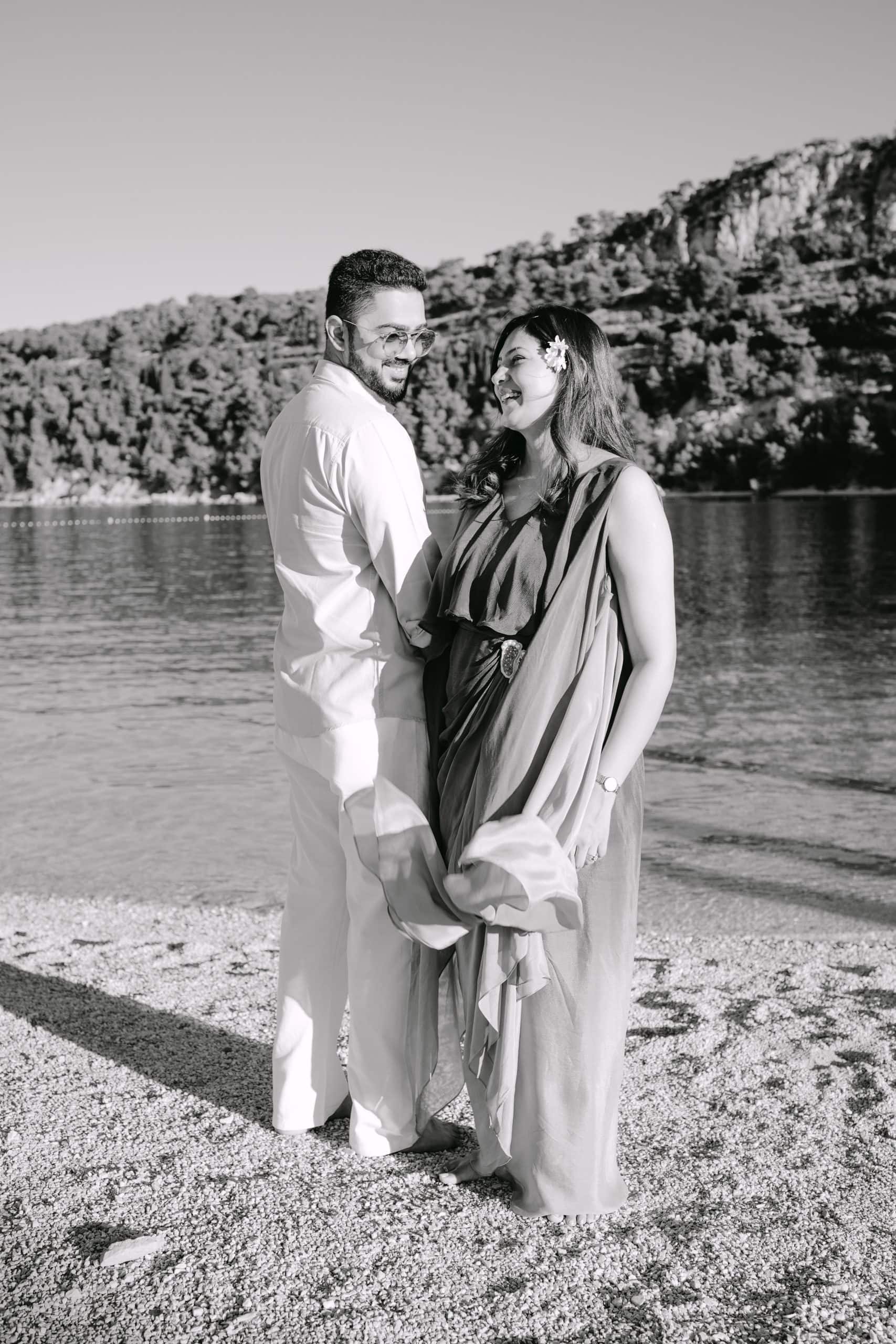 Trudnica grli svog partnera dok se nježno smiješe jedno drugome na trudničkom snimanju u Splitu uz more.