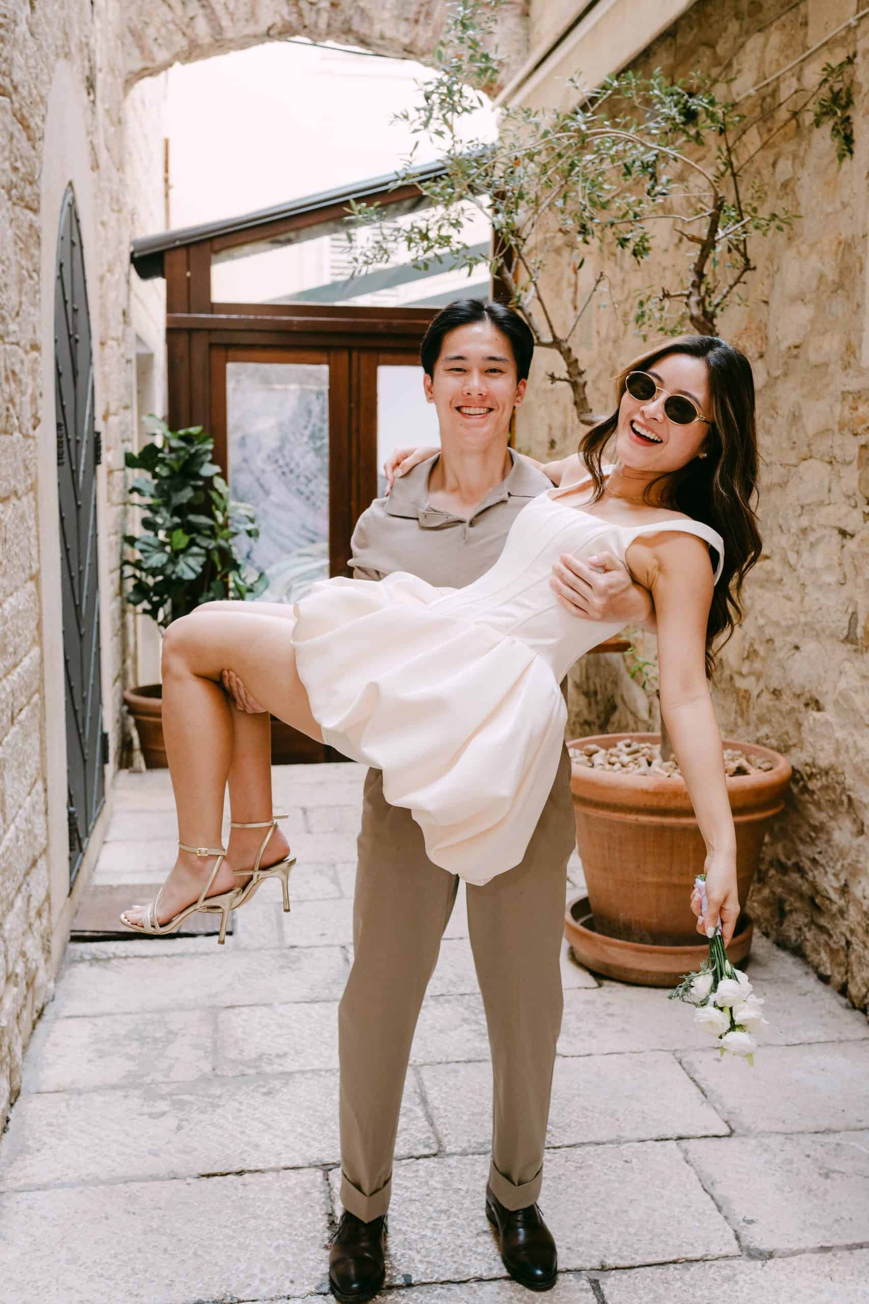 Sretan par u slikovitoj uličici uživa u zajedničkom trenutku uz prirodno osvjetljenje i rustikalni ambijent.