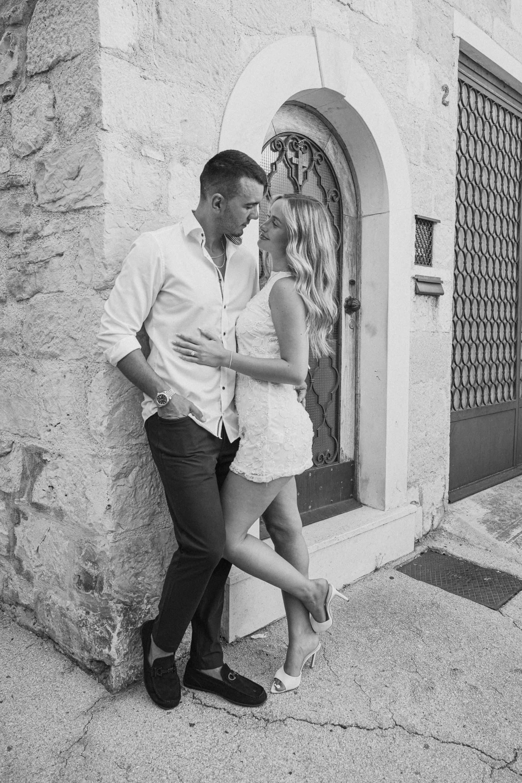 Zaručničko snimanje u staroj jezgri Splita: par naslonjen na kameni zid u romantičnom trenutku.