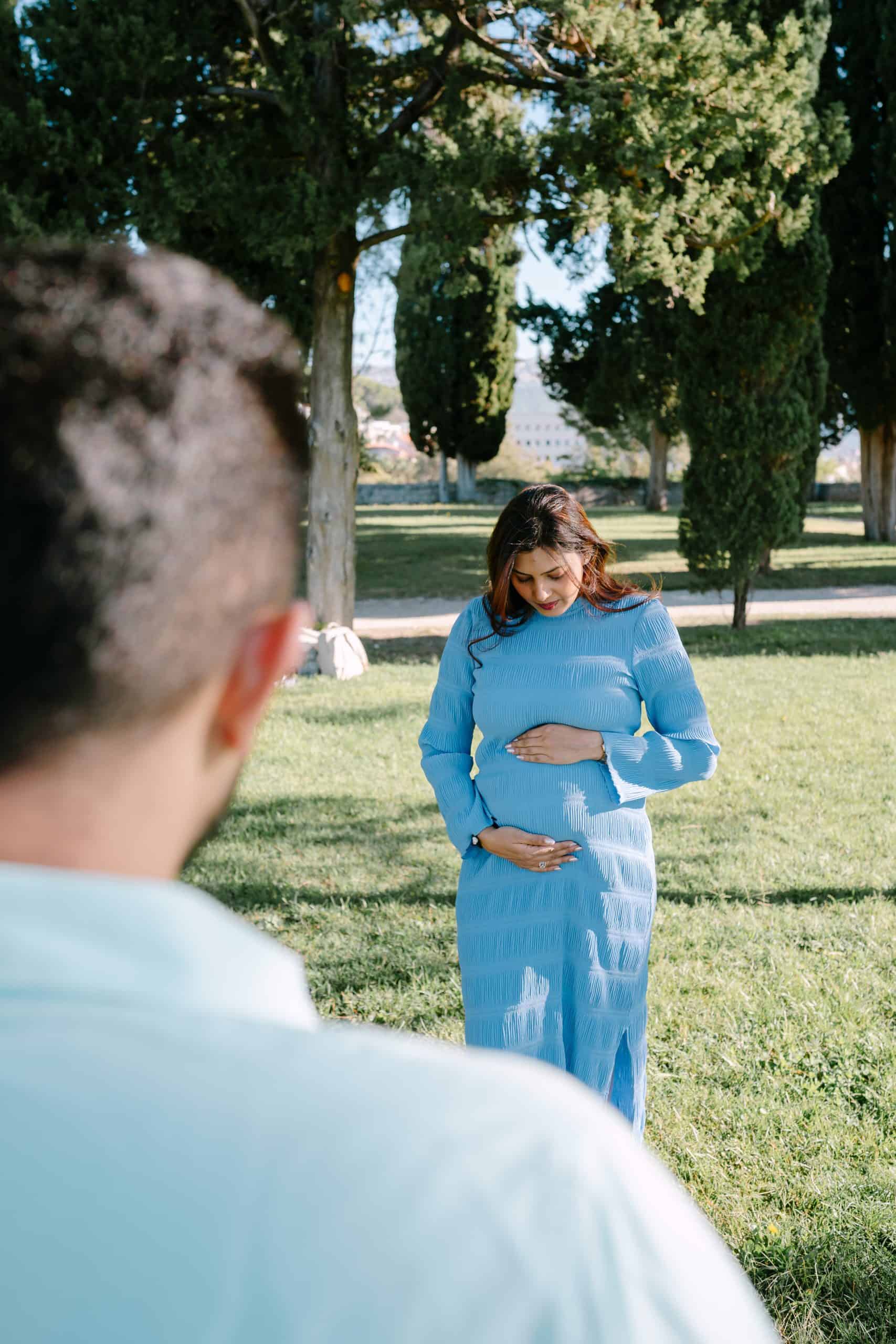 Trudnica grli svoj trbuh dok je on nježno gleda.