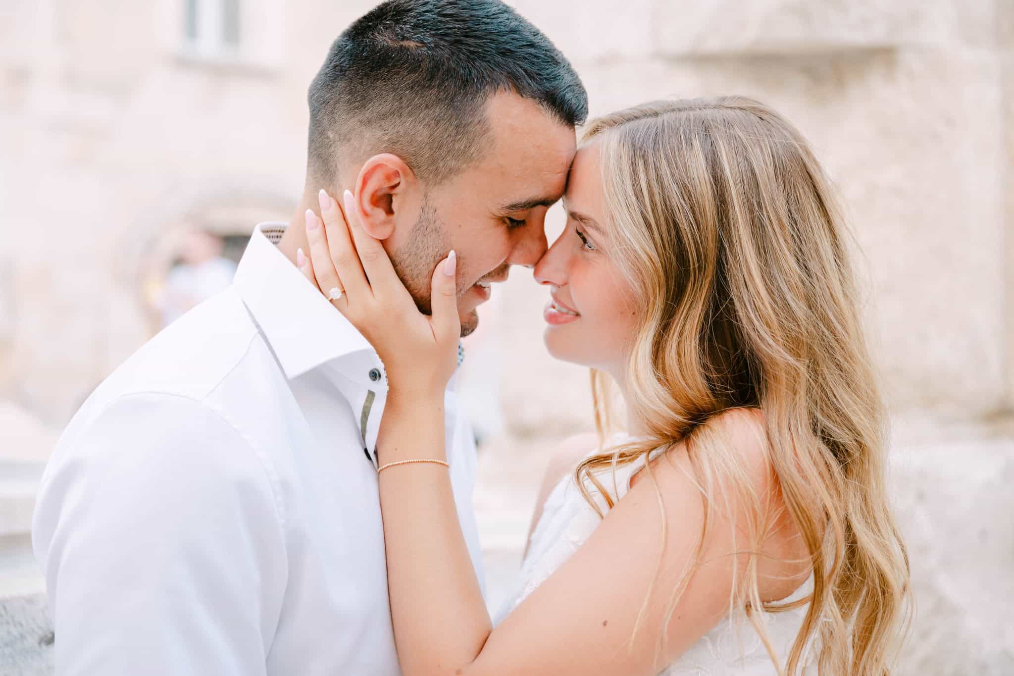Emotivni trenutak para koji se dodiruje čelima dok žena dlanom drži muškarčevo lice, na otvorenom.