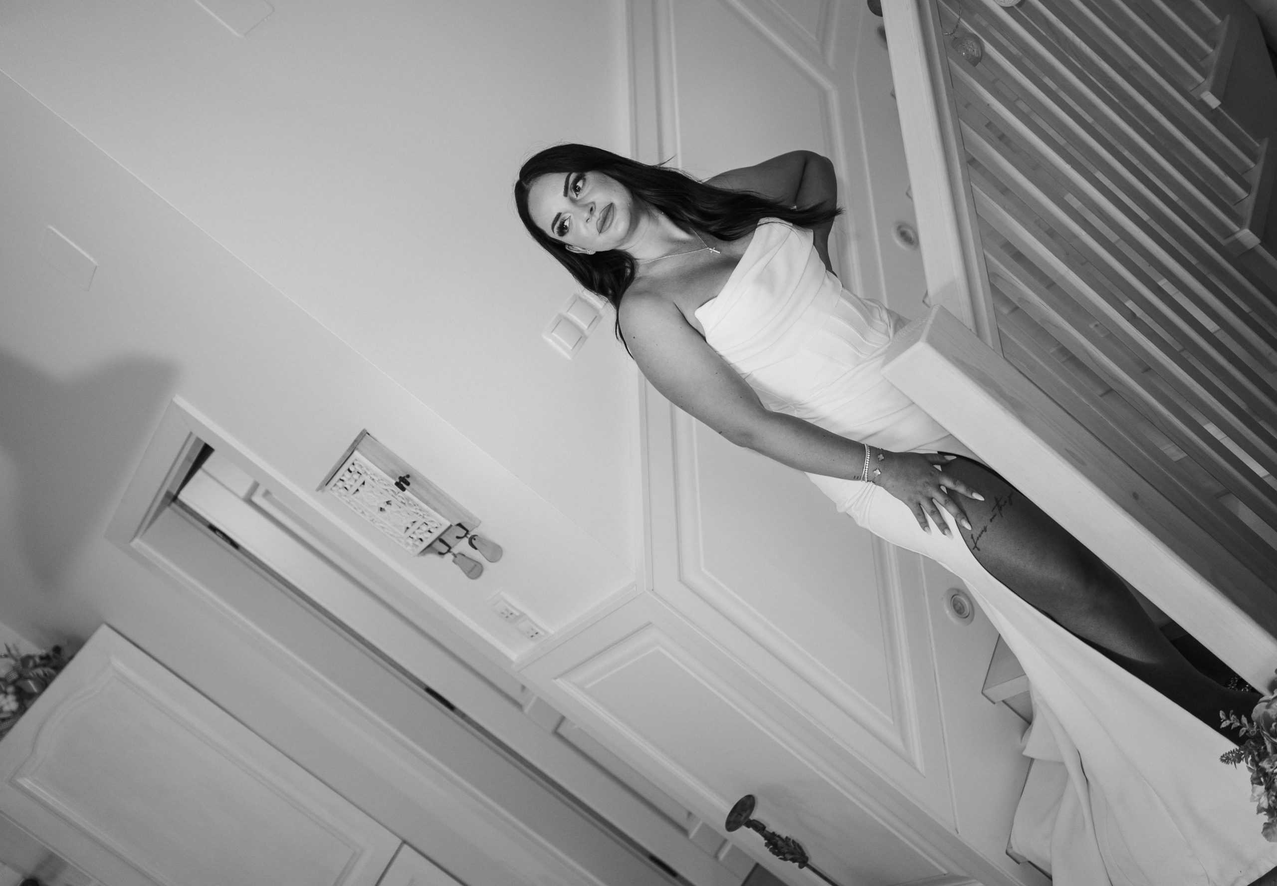 Visokoestetski crno-bijeli portret mladenke koja pozira na stepenicama. Editorial stil vjenčane fotografije s naglaskom na modu i eleganciju.