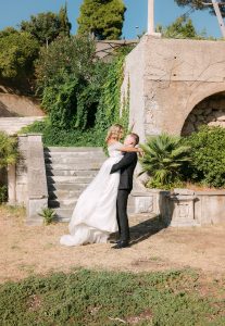 Mladoženja podiže mladenku u naručje ispred starog kamenog zida i stepenica obraslih bršljanom. Romantični wedding session u Dubrovniku.