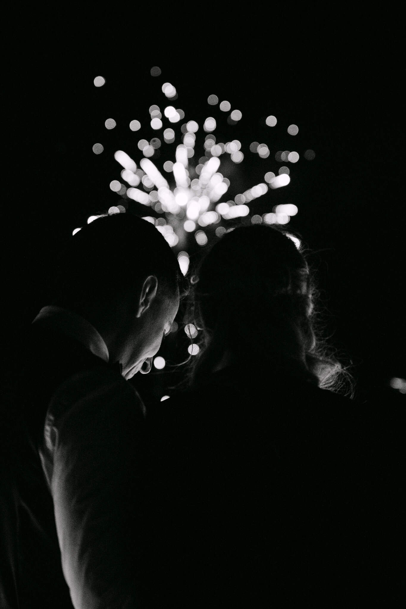 Silueta mladenaca koji gledaju spektakularni vatromet tijekom svadbene proslave u Omišu. Crno-bijela umjetnička fotografija vjenčanja.